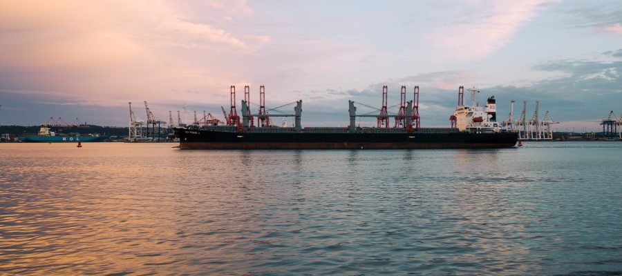 A cargo ship parked at the harbour on a sunny day during sunset